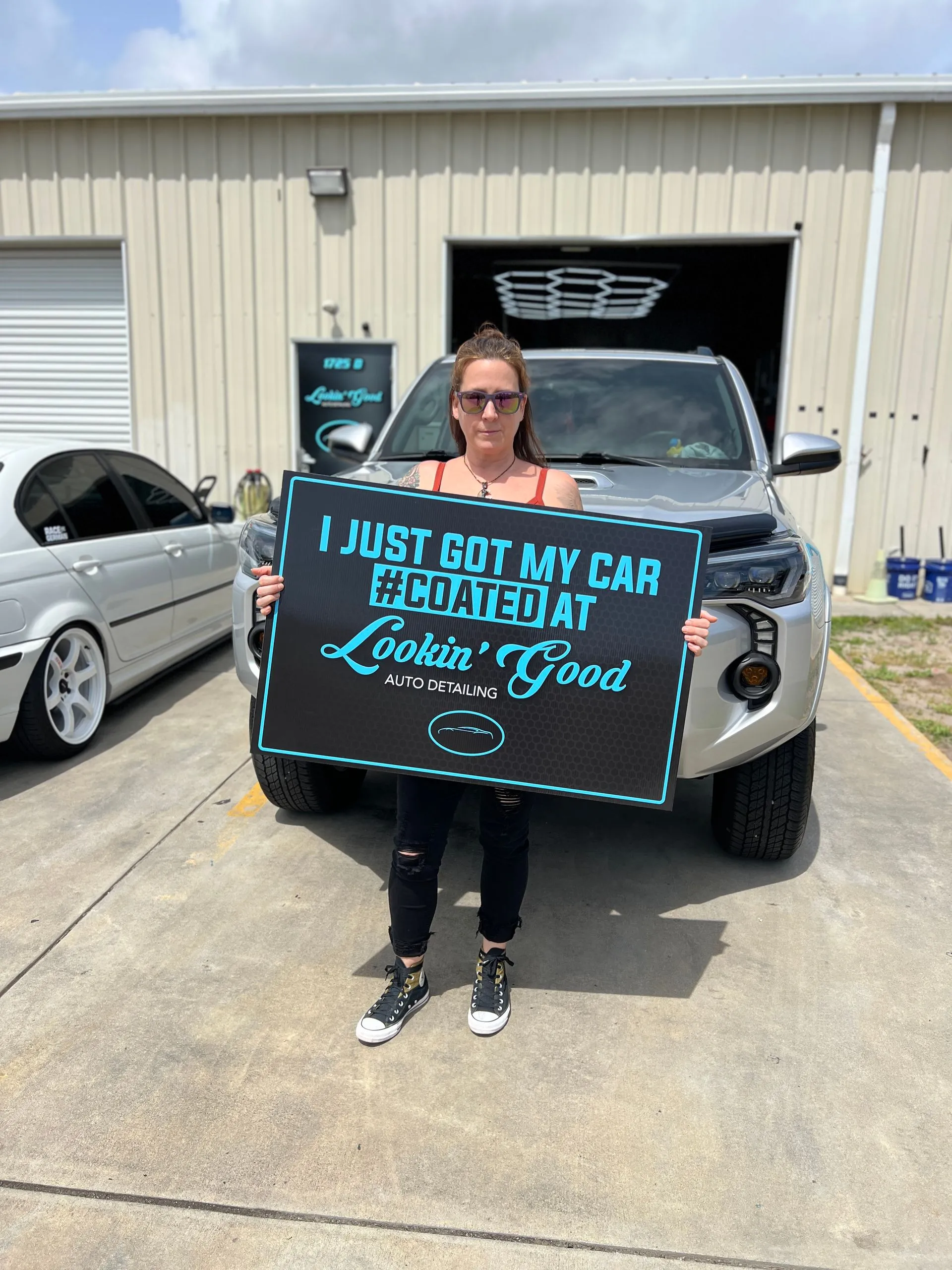 Client holding a #COATED sign beside a coated Toyota 4Runner