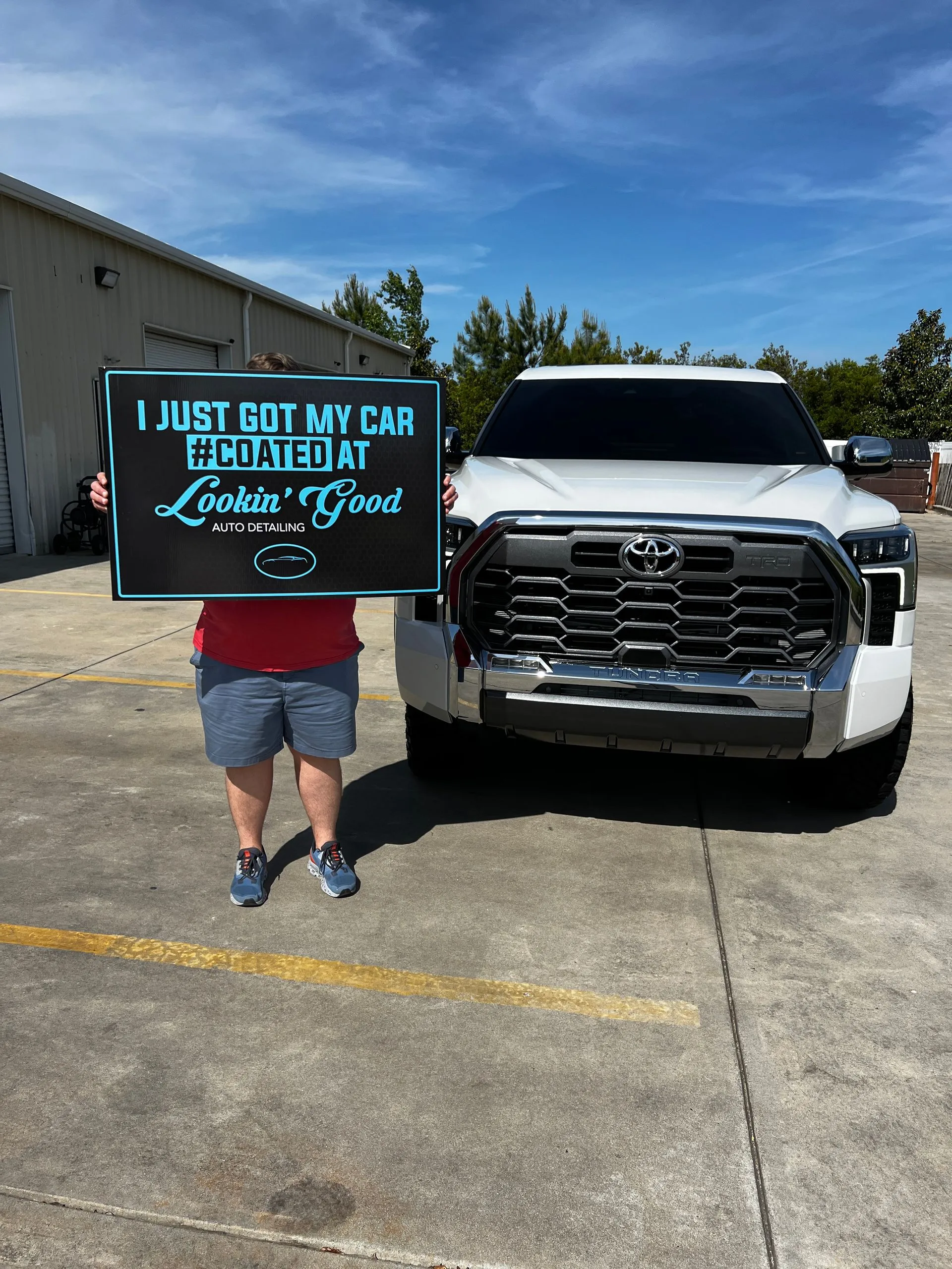 Client holding a #COATED sign beside a coated Toyota Tundra TRD