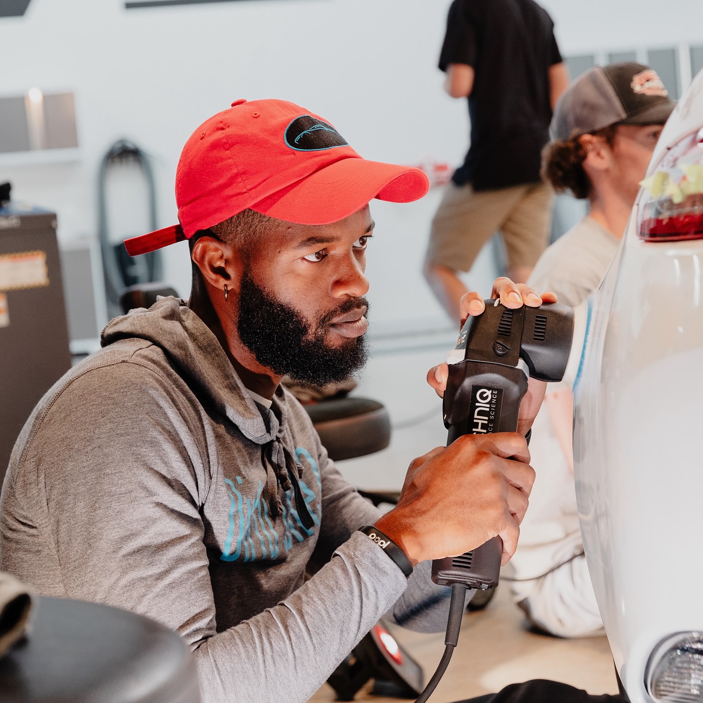 Technician machine polishing a white car at the Gtechniq bench